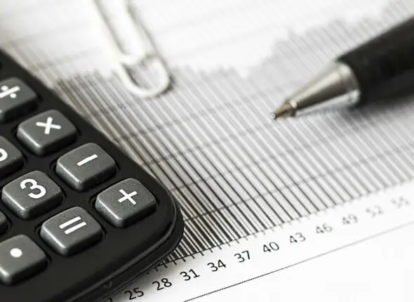 Close-up of a calculator and pen on a bar graph, representing finance and accounting.